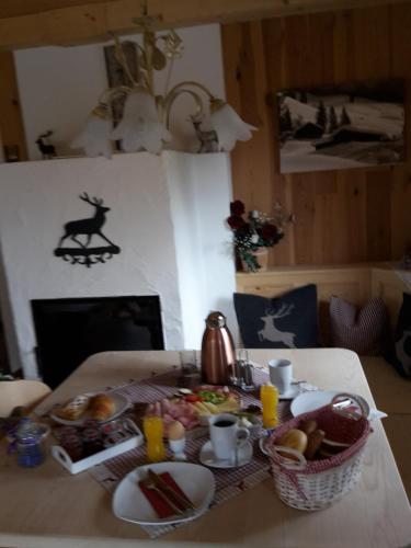 a breakfast table with a tray of food and a fireplace at Bergpension-Ebental in Brixen im Thale