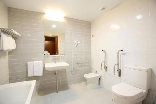 a white bathroom with a toilet and a sink at Evenia Monte Real in Monte Real