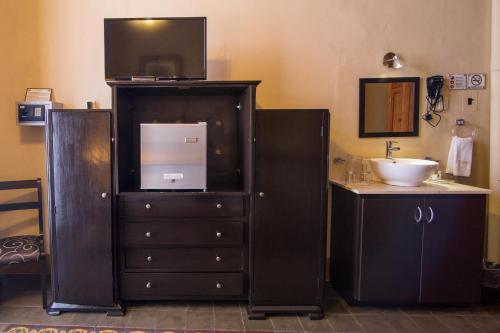 Un baño con lavabo y una cómoda con televisión. en El Gran Hotel, en Mérida