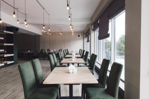 a dining room with wooden tables and green chairs at Zinedine Sport-Hotel in Uzhhorod