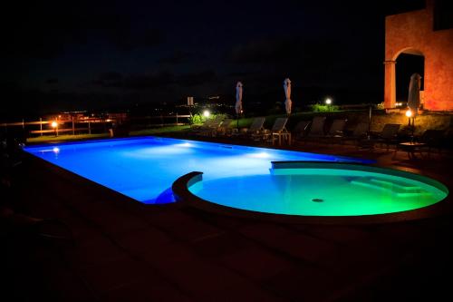 a swimming pool at night with blue lights at Abbaidda Hotel in Valledoria