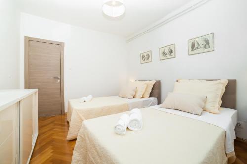 two beds in a room with white walls and wooden floors at Casa Ana in Zadar