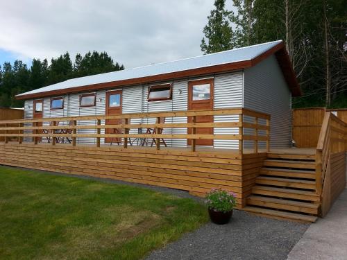 a mobile home with a wooden fence at Guesthouse Hvítafell in Laugar