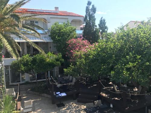 a garden in front of a building with trees and flowers at Guesthouse Punta Mira - Beachfront in Novalja