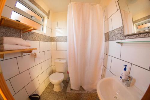 a bathroom with a white shower curtain and a toilet at En Casa de Patricia in Laguna Verde