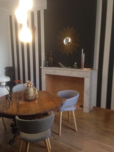 une salle à manger avec une table, des chaises et une cheminée dans l'établissement Rose-INN appartement, à Orange