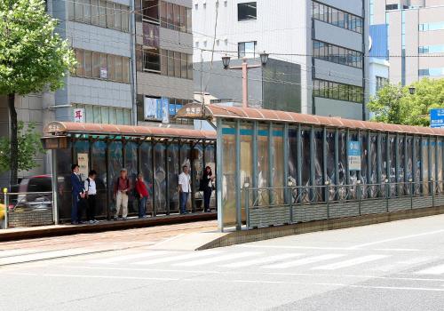 a group of people waiting on a tram in a city at Daiwa Roynet Hotel Hiroshima in Hiroshima