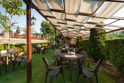 an outdoor restaurant with tables and chairs under awning at Family Hotel Dayana Beach in Sinemorets