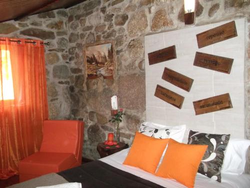 1 dormitorio con cama y pared de piedra en Quinta do Pé Longo - Serra da Estrela, en Cortes do Meio