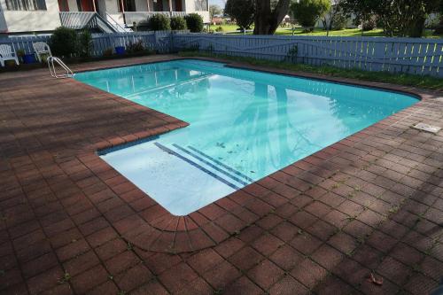 uma piscina com água azul num pátio de tijolos em North End Motel em Huntly