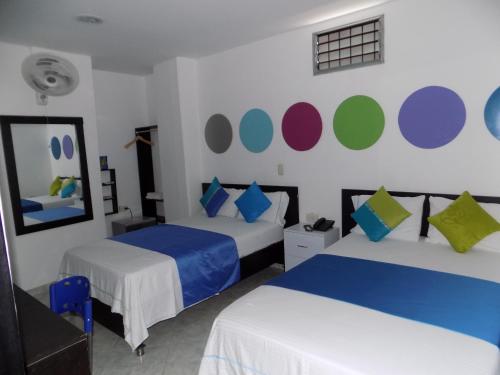 a bedroom with two beds and a wall with colorful circles at Hotel Luna Azul in Florencia
