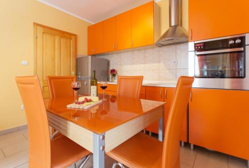 een keuken met een houten tafel en oranje kasten bij Djurovic Apartments Montenegro in Kotor