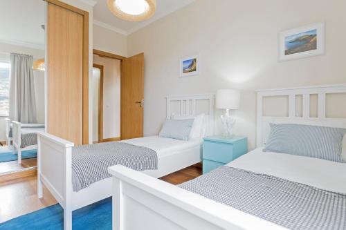 a white bedroom with two beds and a window at Jasmineiro II by An Island Apart in Funchal
