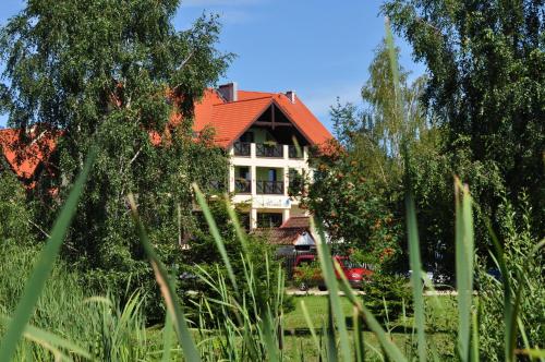 a house with a red roof in a garden at Hotel Santa Monica in Mikołajki