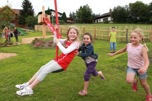 three children jumping on a playground swing at Familien-Appartements Örglwirt's Gut in Mariapfarr