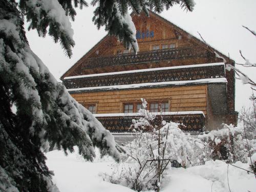 a building covered in snow next to a tree at Willa Asia in Wisła