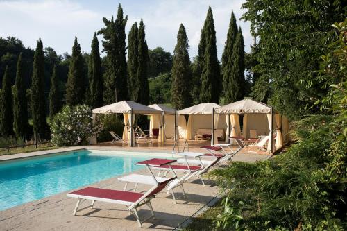 a beach with a pool, chairs, and tables at Agriturismo La Topaia in Borgo San Lorenzo