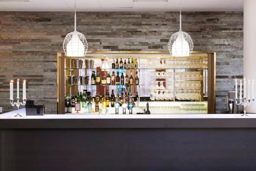 a bar with two pendant lights and a shelf of bottles at Motel L Stockholm Älvsjö in Stockholm