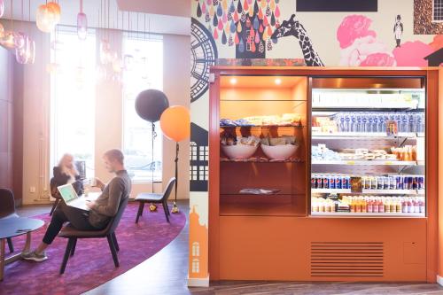 a person sitting in a chair in front of a refrigerator at Motel L Stockholm Älvsjö in Stockholm
