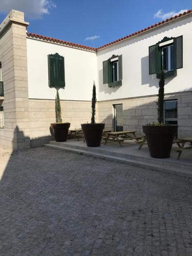 a building with benches and trees in a courtyard at Hotel Medieval® de Penedono in Penedono