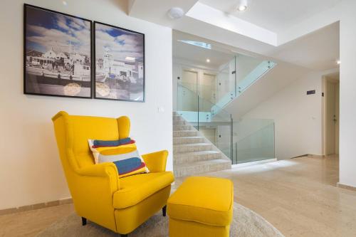 a yellow chair in a living room with stairs at Villas Arausana & Antonina in Vodice