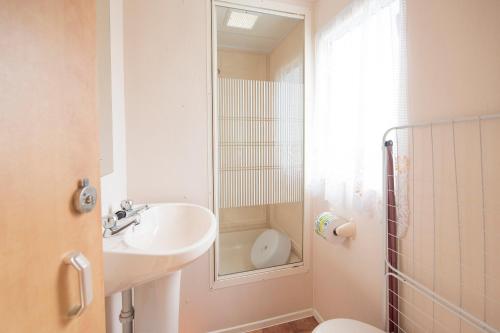 La salle de bains est pourvue d'un lavabo, de toilettes et d'un miroir. dans l'établissement Holiday Lodge, à Pogorzelica