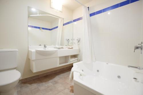 a bathroom with a sink and a tub and a toilet at Ventura Inn & Suites Hamilton in Hamilton