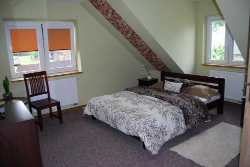 a bedroom with a bed and a chair and windows at Kamienna Zagroda in Białowieża
