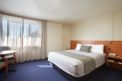 a hotel room with a bed and a desk and a window at Ventura Inn & Suites Hamilton in Hamilton