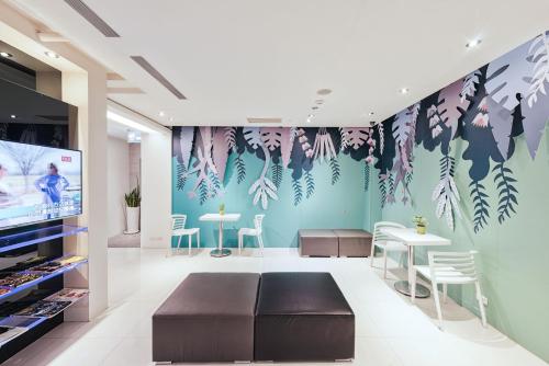 a room with a couch and tables and a wall with plants at CityInn Hotel Taipei Station Branch II in Taipei