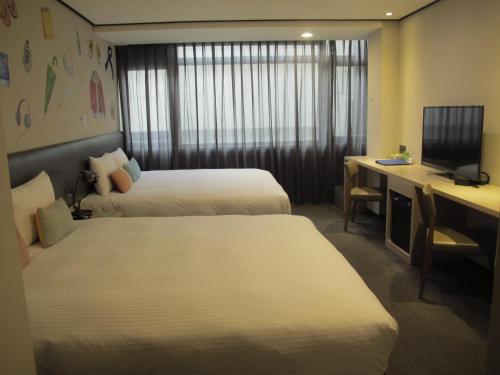 a hotel room with two beds and a desk at Energy Inn in Taipei