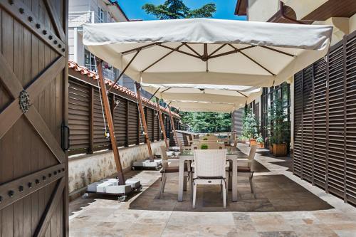 a patio with tables and chairs under an umbrella at Sarıkonak Boutique & Spa Hotel Amasya in Boğazköy