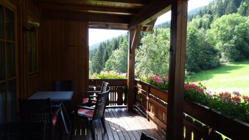 a screened porch with a table and chairs and flowers at Ferienhaus Enzi in Weissbriach