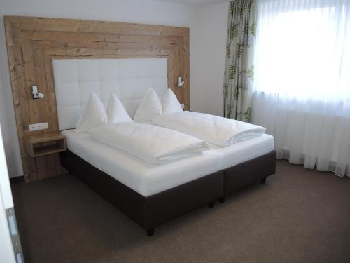 a bedroom with a large bed with white pillows at Hotel Berghof in Millstatt