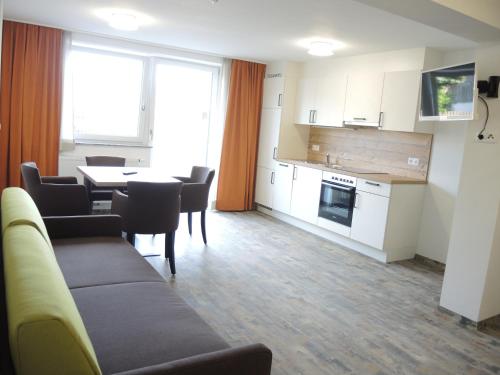 a living room with a table and a kitchen at Hotel Berghof in Millstatt