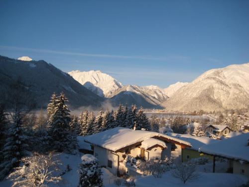 a house covered in snow with mountains in the background at Appartements Rofangarten in Maurach