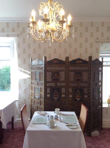 a dining room with a table and a chandelier at Inglenook Guest House in Ingleton 