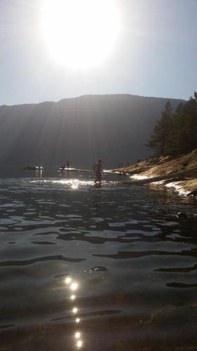 a person standing in the water on a beach at Rongahuset BnB in Evanger