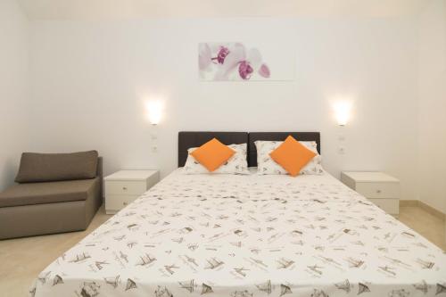 a bedroom with a bed with orange pillows and a chair at Pansion Makina in Vodice