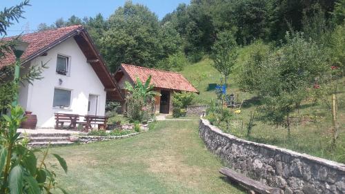 a house with a stone wall next to a yard at Holiday Home Nektar Park in Bihać