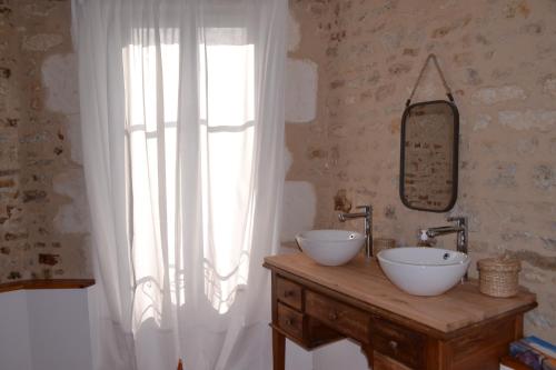 een badkamer met 2 wastafels en een groot raam bij La maison de Thiré in Thiré
