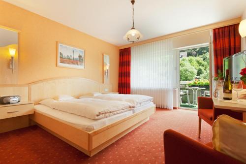 a bedroom with a large bed and a balcony at Gästehaus Behle-Schäperken in Willingen