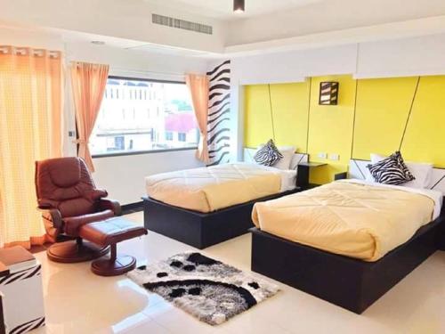 a bedroom with two beds and a chair in it at Win Hotel Phayao in Phayao
