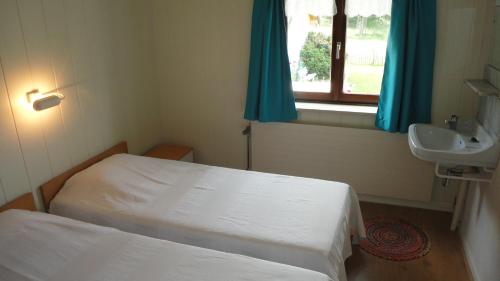 a room with two beds and a sink and a window at Lardinois vakantieverhuur in Beutenaken