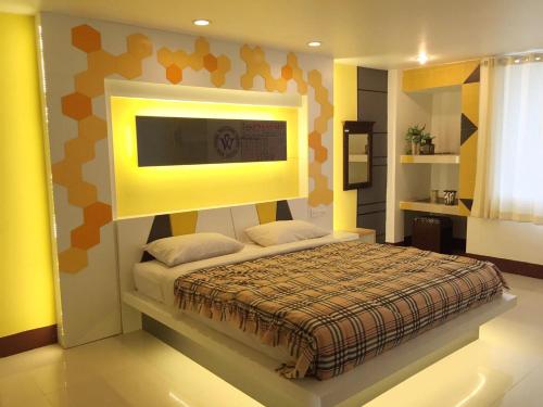 a bedroom with a bed with a tv on the wall at Win Hotel Phayao in Phayao
