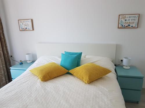 a bed with yellow and blue pillows on it at Biandada Apartments in Mamaia Sat/Năvodari