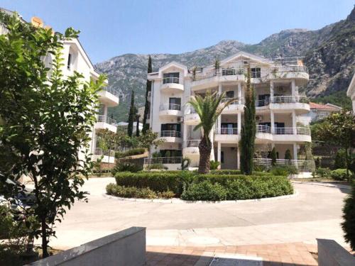 a large white apartment building with palm trees and mountains at Roman Garden Apartment in Risan