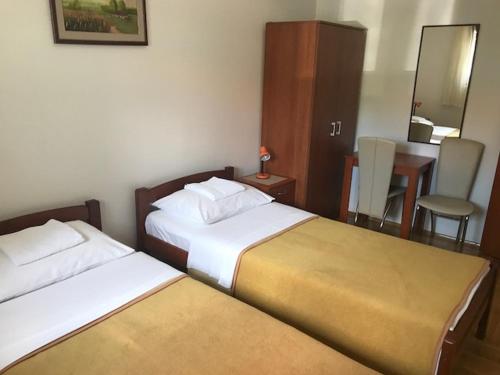 a hotel room with two beds and a table with a chair at Guesthouse Vujacic in Cetinje