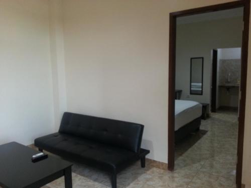 a living room with a black couch and a mirror at Discovery Homestay in Makassar