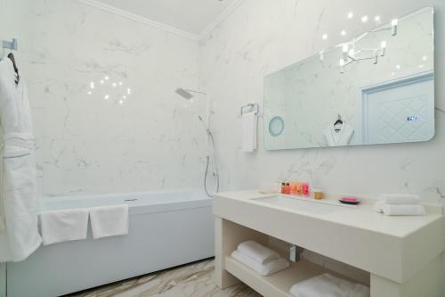 a white bathroom with a sink and a tub and a mirror at The ONE Hotel Astana in Astana